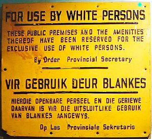 Ecrit en anglais (haut) et allemand (bas): Les lieux publics et les équipements de sont réservés à l'usage exclusif des personnes  blanches