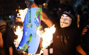 Des manifestants brûlent un album de collant de la Coupe du Monde de la FIFA Brésil 2014, lors d'une manifestation contre le prochain tournoi de la FIFA à Rio de Janeiro le 15 mai 2014. – Photo : Getty Images