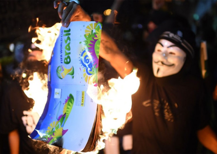 Des manifestants brûlent un album de collant de la Coupe du Monde de la FIFA Brésil 2014, lors d'une manifestation contre le prochain tournoi de la FIFA à Rio de Janeiro le 15 mai 2014. – Photo : Getty Images