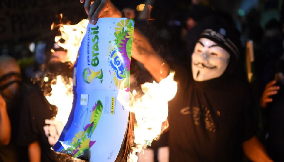 Des manifestants brûlent un album de collant de la Coupe du Monde de la FIFA Brésil 2014, lors d'une manifestation contre le prochain tournoi de la FIFA à Rio de Janeiro le 15 mai 2014. – Photo : Getty Images